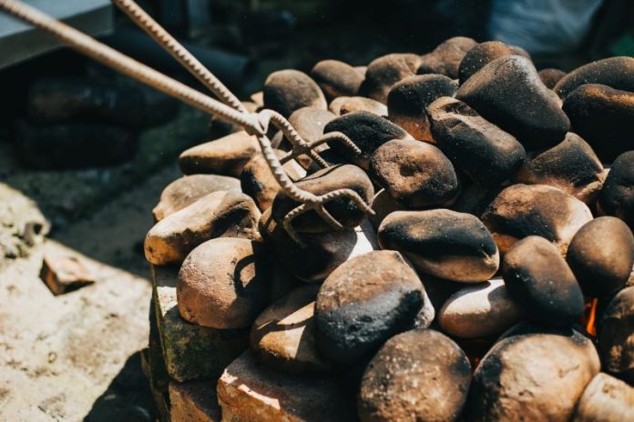 heated cooking stones being moved into place