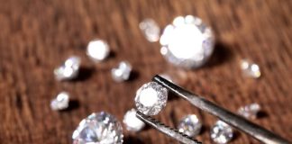 multiple lab grown diamonds with one being held up by tweezers