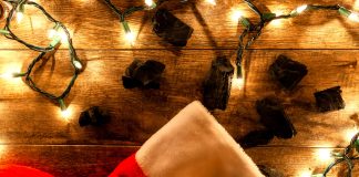 coal pieces next to a christmas stocking with lit twinkle lights