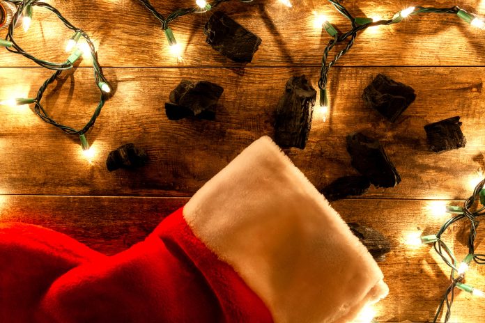 coal pieces next to a christmas stocking with lit twinkle lights